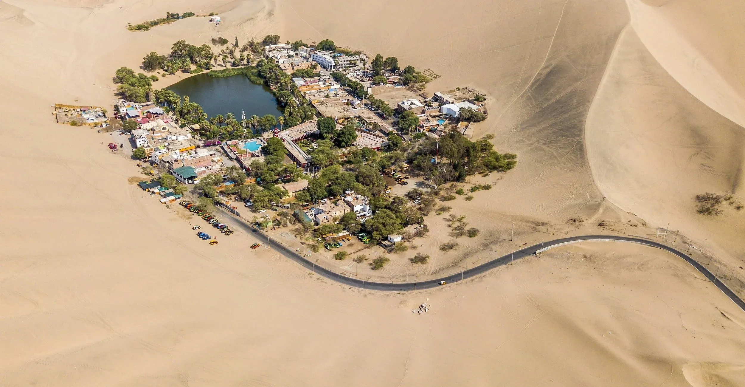 Vista aérea del oasis de Huacachina rodeado de dunas en Ica