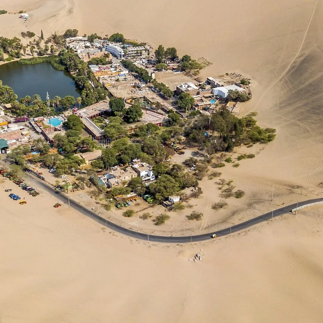 Vista aérea del oasis de Huacachina rodeado de dunas en Ica