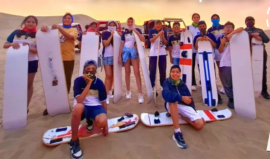 Promoción escolar con tablas de sandboard en Huacachina
